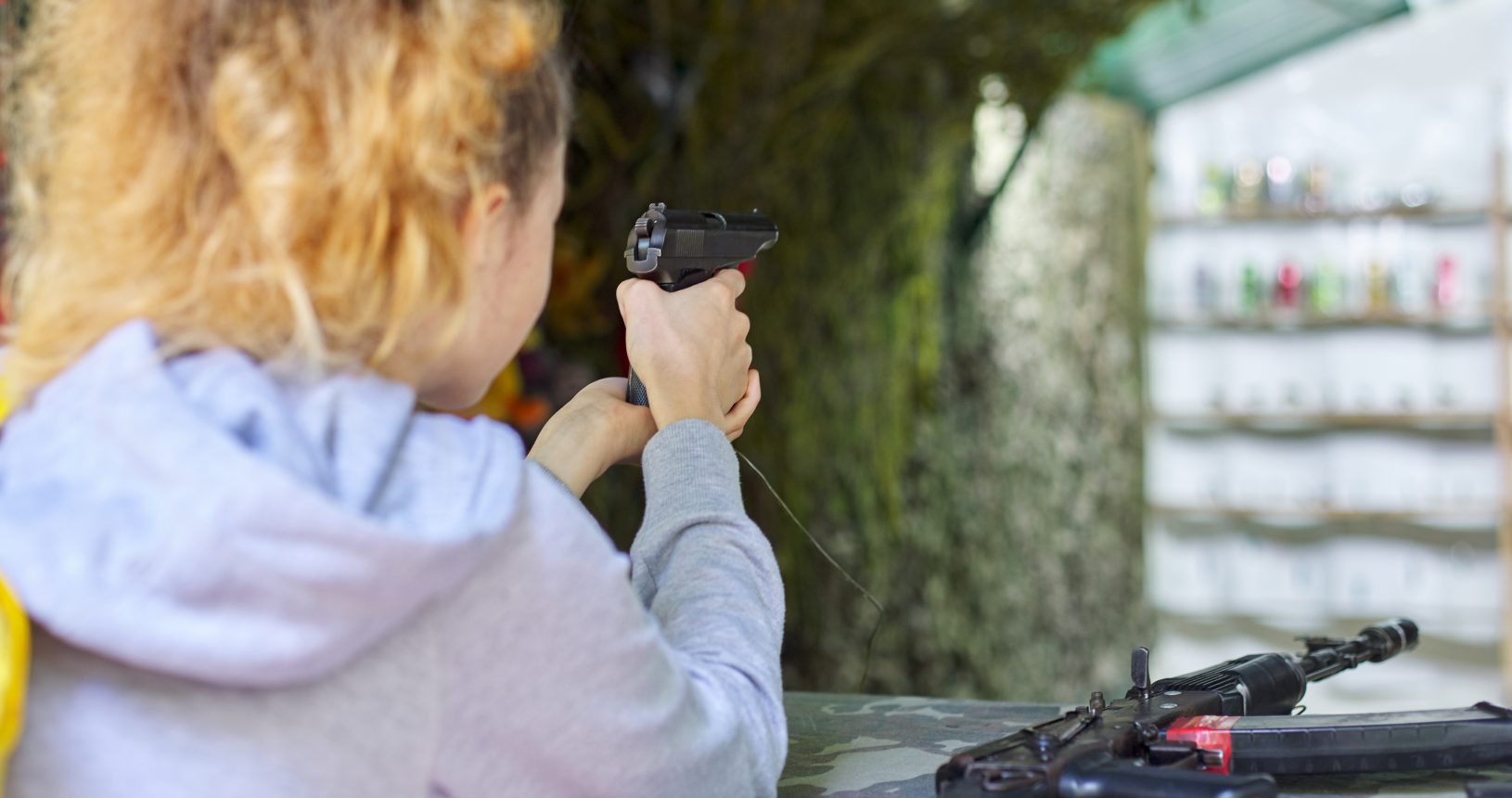 Close-up of teenage girl shooting training pistol at shooting range